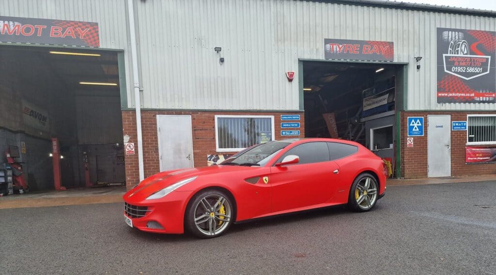Red Ferrari parked outside our garage building