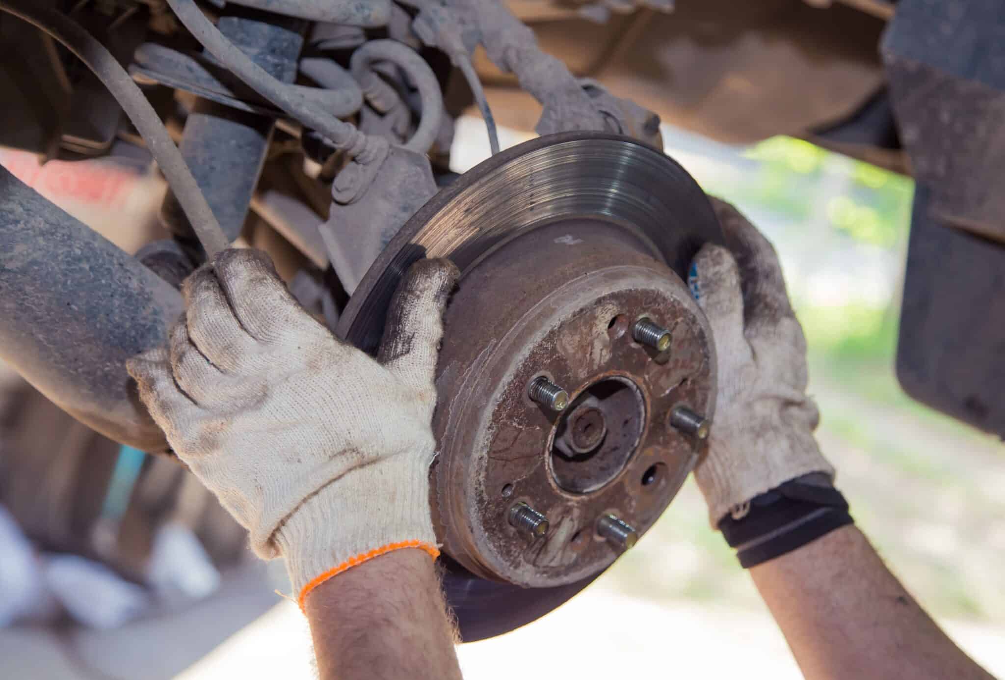 Stock image of a mechanic replacing a car brake disc during brake repair work